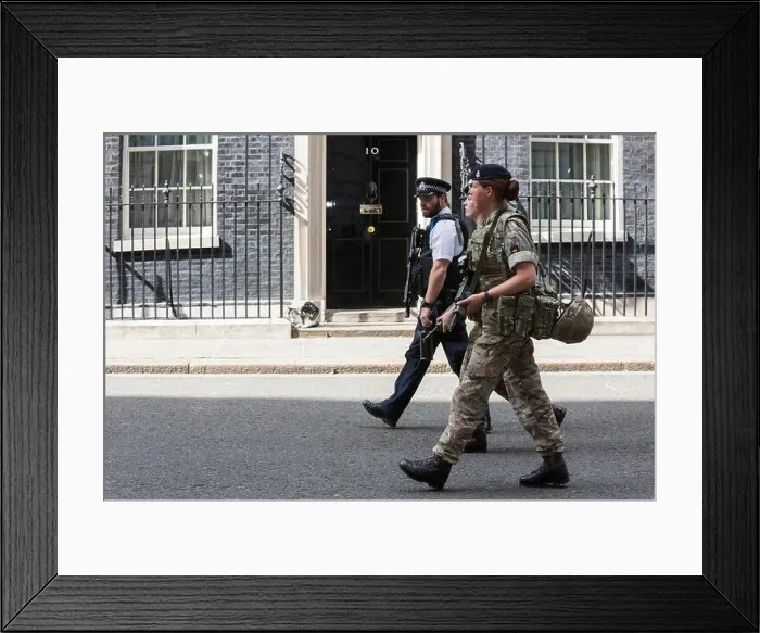 Framed Print : London, UK. 24 May 2017. A police officer and two female soldiers walk past the front door of No Framed Print : London, UK. 24 May 2017. A police officer and two female soldiers walk past the front door of No