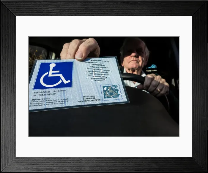 Framed Print : Handicapped elderly man placing EU parking card for people with disabilities – Blue Badge - behind windscreen of car Framed Print : Handicapped elderly man placing EU parking card for people with disabilities – Blue Badge - behind windscreen of car