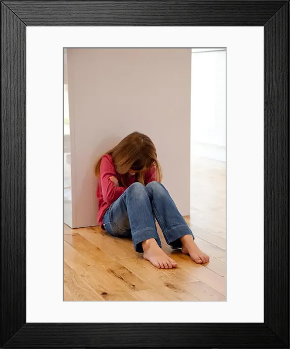 Framed Print : Young girl sat unhappy on the floor Framed Print : Young girl sat unhappy on the floor