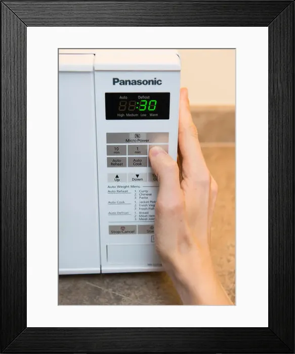 Framed Print : A person setting the timer on a microwave Framed Print : A person setting the timer on a microwave