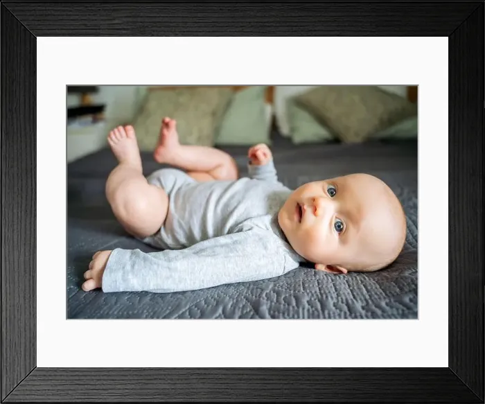 Framed Print : Cute toddler boy lying on bed at home Framed Print : Cute toddler boy lying on bed at home