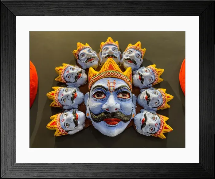 Framed Print : Handmade colorful tribal look of Ravan face mask souvenir hanging on plain black background. Selective focus on object Framed Print : Handmade colorful tribal look of Ravan face mask souvenir hanging on plain black background. Selective focus on object