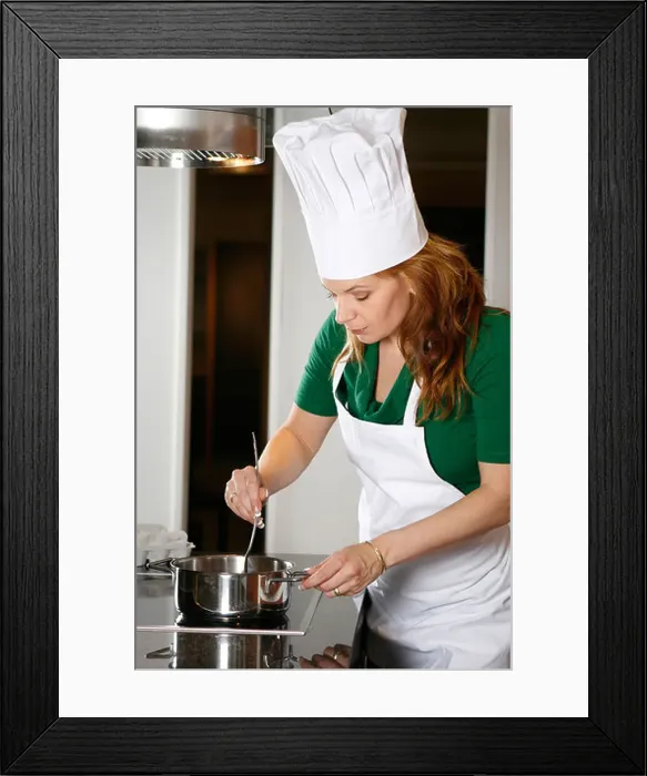 Framed Print : Woman wearing apron and chef's hat cooking in kitchen Framed Print : Woman wearing apron and chef's hat cooking in kitchen