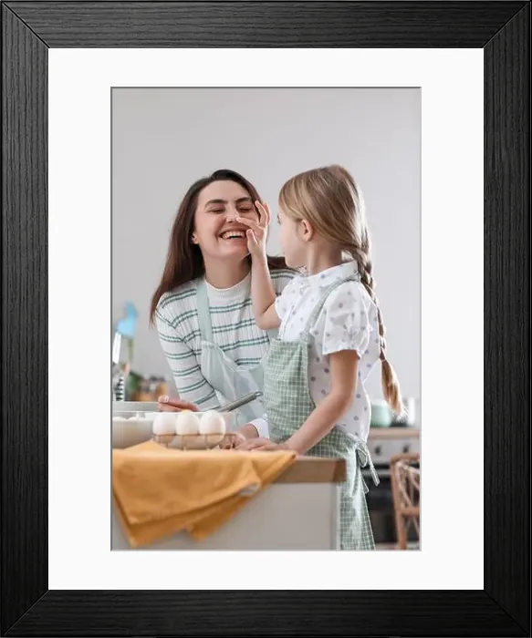 Framed Print : Little girl touching her mother's nose while cooking in kitchen on Easter day Framed Print : Little girl touching her mother's nose while cooking in kitchen on Easter day