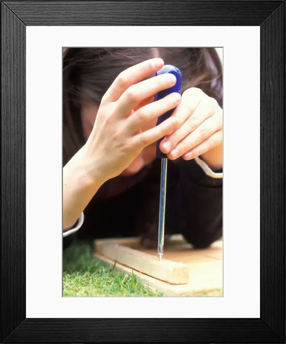 Framed Print : young girl screwing a nextbox together