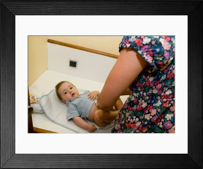 Framed Print : mother changing nappies on a six month year old baby Framed Print : mother changing nappies on a six month year old baby