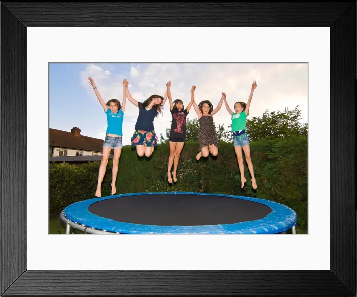 Framed Print : Horizontal close up portrait of a group of girl friends jumping on a trampoline in a garden Framed Print : Horizontal close up portrait of a group of girl friends jumping on a trampoline in a garden