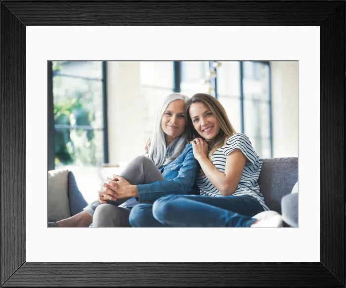 Framed Print : Daughter holding mother in her arms, sitting on couch Framed Print : Daughter holding mother in her arms, sitting on couch