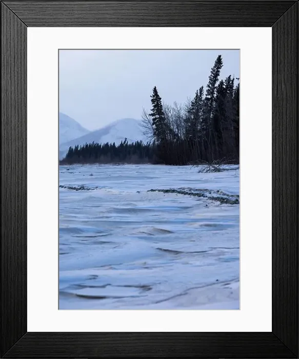 Framed Print : Patterns in snow on frozen river with trees and mountains in the background on a cloudy winter day in interior Alaska