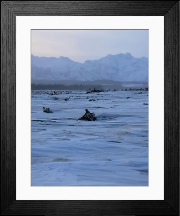 Framed Print : Trees in the snow on a frozen river with mountains in the background on a winter day in Alaska Framed Print : Trees in the snow on a frozen river with mountains in the background on a winter day in Alaska