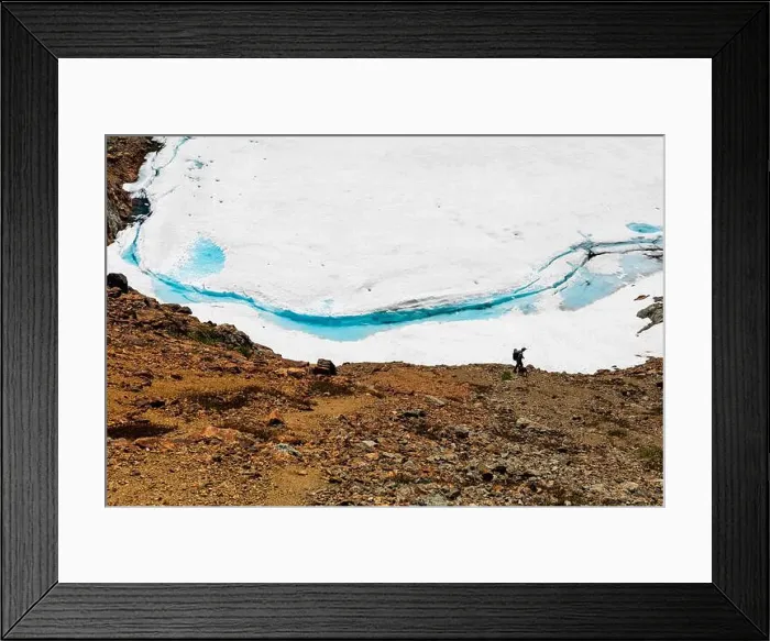 Framed Print : A man and dog hike down to frozen snow covered lake with vibrant blue Framed Print : A man and dog hike down to frozen snow covered lake with vibrant blue