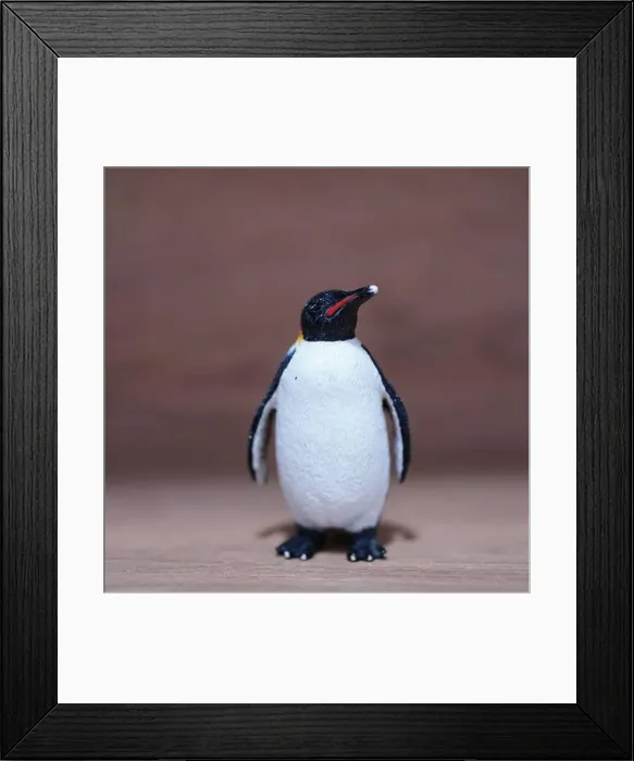 Framed Print : A closeup shot of a mini penguin toy figure on a wooden surface