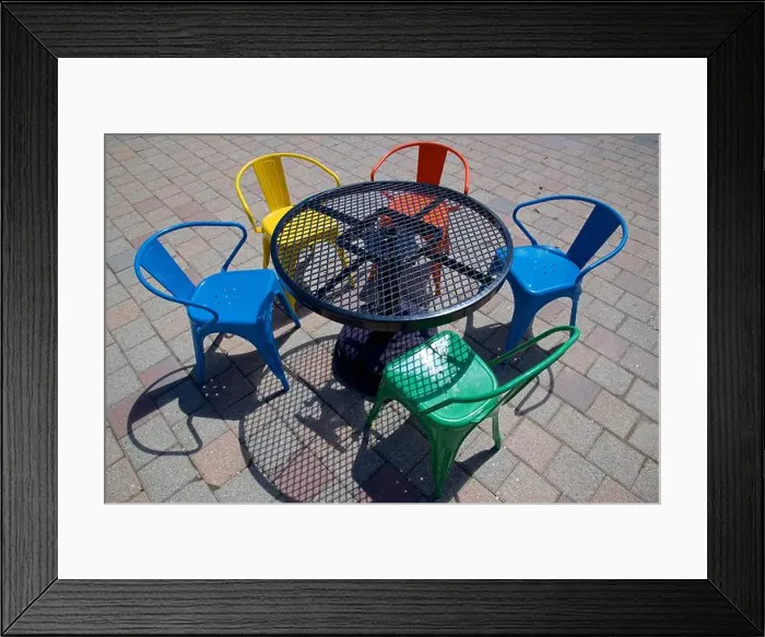 Framed Print : Light and shadow of the multi coloured chairs and table Framed Print : Light and shadow of the multi coloured chairs and table