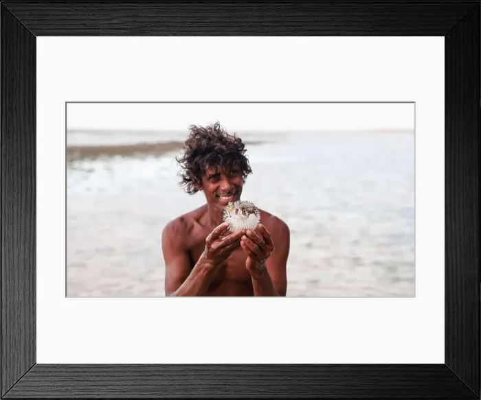 Framed Print : A man holds a pufferfish while standing in shallow waters off the coast of Socotra, enjoying the beauty of nature Framed Print : A man holds a pufferfish while standing in shallow waters off the coast of Socotra, enjoying the beauty of nature