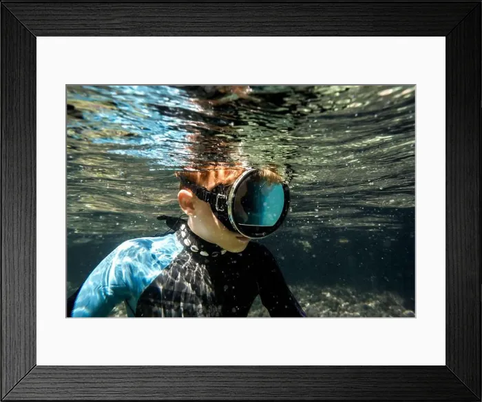 Framed Print : A young snorkeler explores the vibrant underwater sea life in the crystal-clear waters off the coast of Menorca, Spain