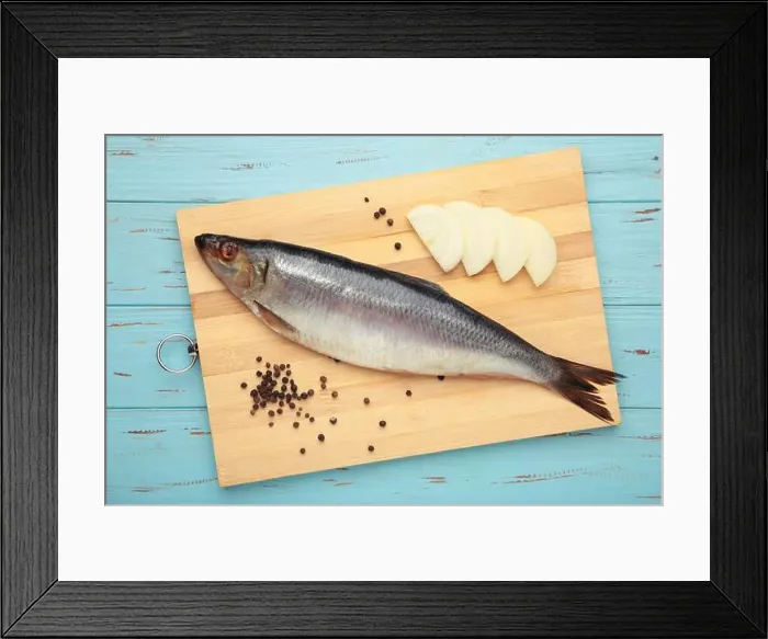 Framed Print : Fresh herring fish on cutting board on blue wooden background. Top view