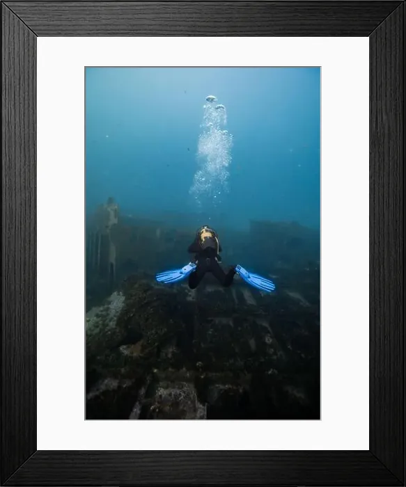 Framed Print : A scuba diver with blue fins hovers near a sunken shipwreck enveloped in the tranquility of the underwater world Framed Print : A scuba diver with blue fins hovers near a sunken shipwreck enveloped in the tranquility of the underwater world