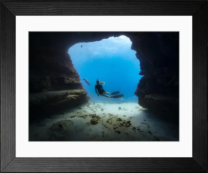 Framed Print : A young female free diving down into a cave doorway accompanied by a green sea turtle with clear blue water Framed Print : A young female free diving down into a cave doorway accompanied by a green sea turtle with clear blue water