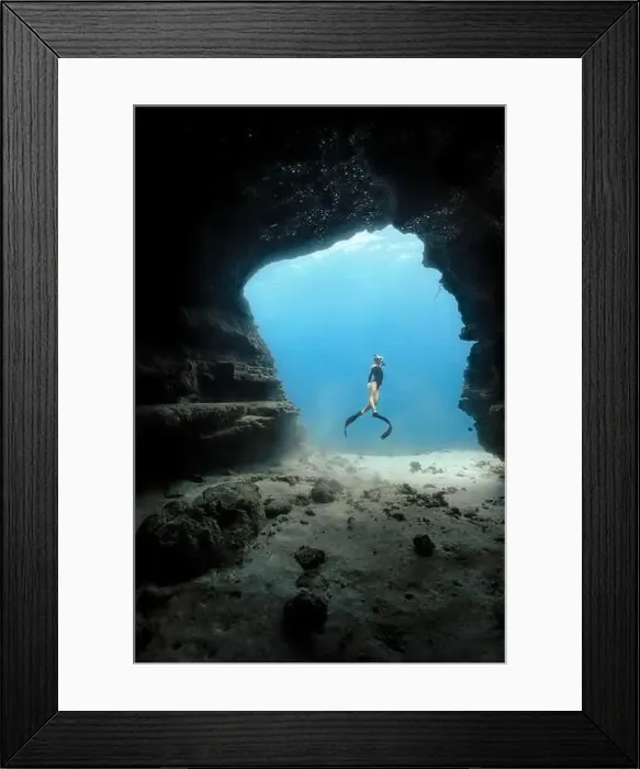 Framed Print : A young female free diving down into a cave doorway in the clear blue waters of Hawaii framed by shadowy cave walls Framed Print : A young female free diving down into a cave doorway in the clear blue waters of Hawaii framed by shadowy cave walls