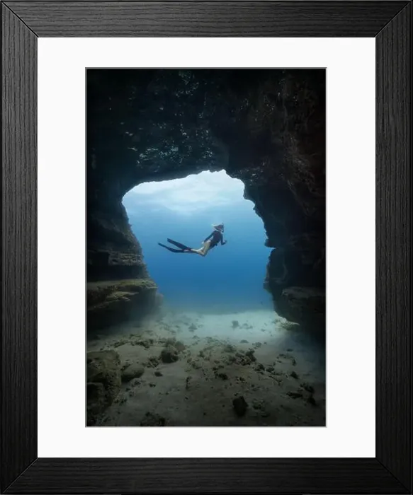 Framed Print : A young female free diving down into a cave doorway in the clear blue waters of Hawaii framed by shadowy cave walls Framed Print : A young female free diving down into a cave doorway in the clear blue waters of Hawaii framed by shadowy cave walls