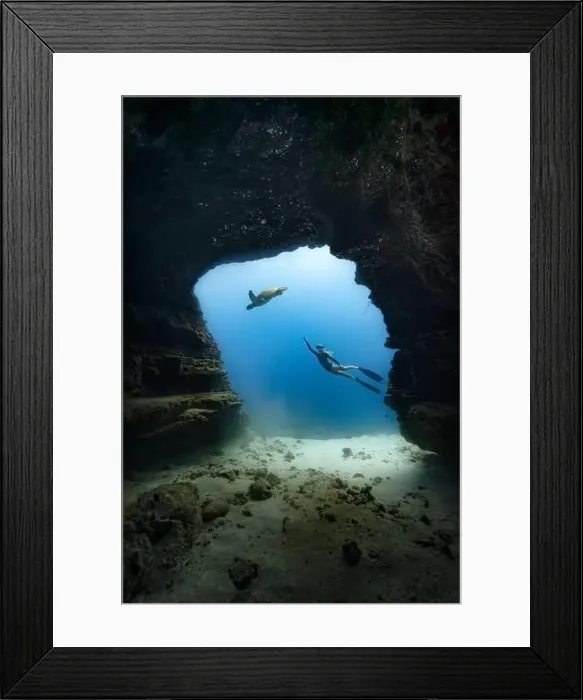Framed Print : A young female free diving down into a cave doorway accompanied by a green sea turtle w / clear blue water Framed Print : A young female free diving down into a cave doorway accompanied by a green sea turtle w / clear blue water