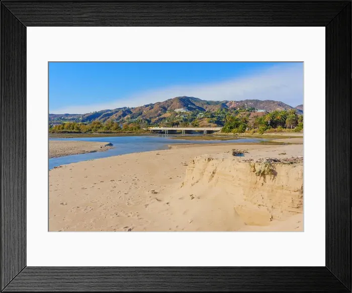 Framed Print : Tranquil scene of a riverbank at Malibu Beach, showcasing soft sandy edges and distant mountains under a clear blue sky Framed Print : Tranquil scene of a riverbank at Malibu Beach, showcasing soft sandy edges and distant mountains under a clear blue sky