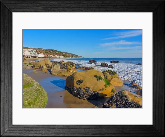 Framed Print : Large rocky shoreline of Malibu Beach featuring homes in the background against a clear sky Framed Print : Large rocky shoreline of Malibu Beach featuring homes in the background against a clear sky