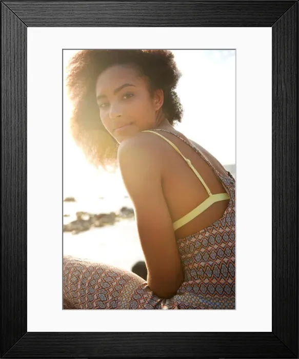 Framed Print : Portrait of smiling teenage girl sitting on sea shore during sunny day Framed Print : Portrait of smiling teenage girl sitting on sea shore during sunny day