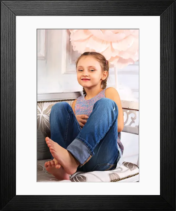 Framed Print : Beautiful laughing kid girl sitting on the bench in blue jeans and fashion blouse looking happy. Studio portrait Framed Print : Beautiful laughing kid girl sitting on the bench in blue jeans and fashion blouse looking happy. Studio portrait