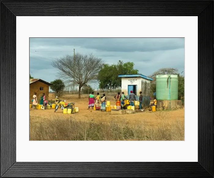 Framed Print : A group of African women and children queue to fill up water containers at a water kiosk in rural Kenya Framed Print : A group of African women and children queue to fill up water containers at a water kiosk in rural Kenya