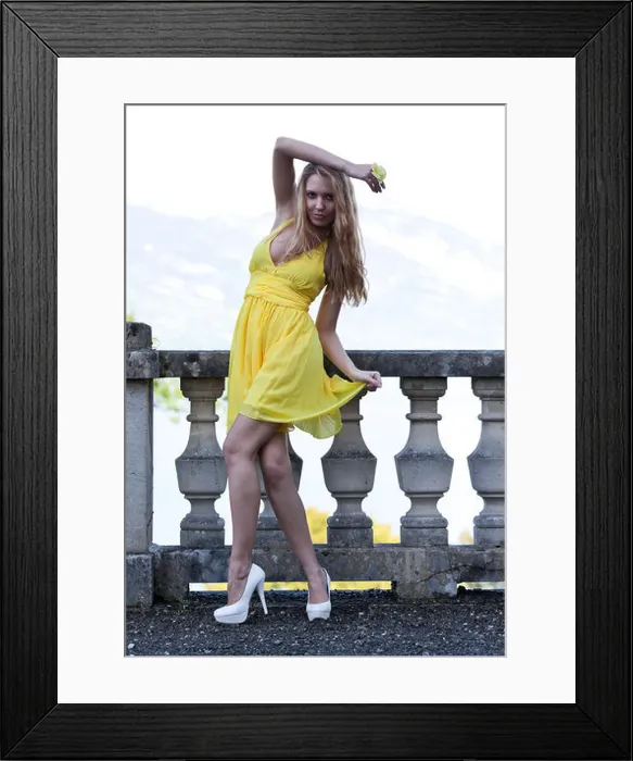 Framed Print : Young woman posing in a yellow dress with white high heels in front of a balustrade Framed Print : Young woman posing in a yellow dress with white high heels in front of a balustrade