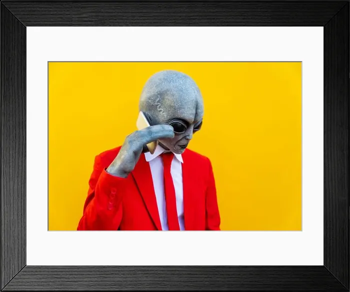 Framed Print : Portrait of man wearing alien costume and bright red suit using smart phone Framed Print : Portrait of man wearing alien costume and bright red suit using smart phone