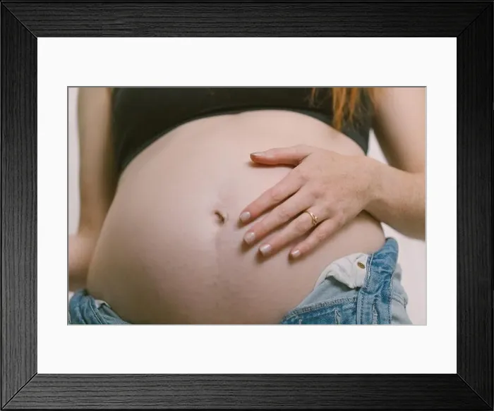 Framed Print : a woman's white hand on pregnant belly wearing jewelry Framed Print : a woman's white hand on pregnant belly wearing jewelry