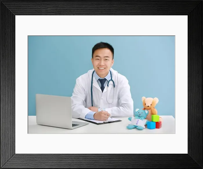 Framed Print : Handsome pediatrician doctor with laptop and teddy bear in office Framed Print : Handsome pediatrician doctor with laptop and teddy bear in office