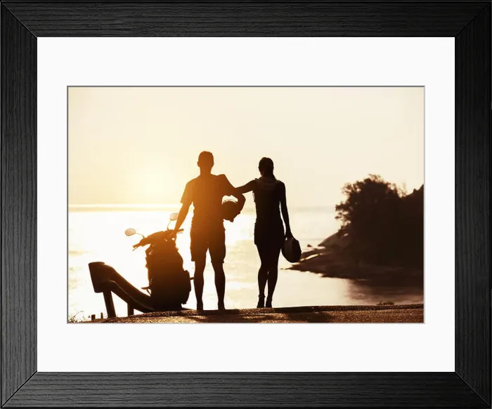 Framed Print : Couple's silhouettes stands with motorcycle against sunset sea bay