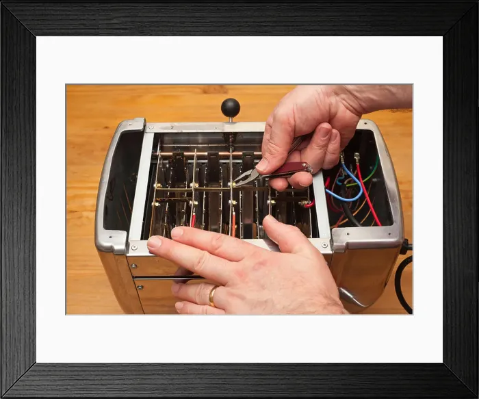 Framed Print : A MODEL RELEASED man mending a toaster in the Uk Framed Print : A MODEL RELEASED man mending a toaster in the Uk