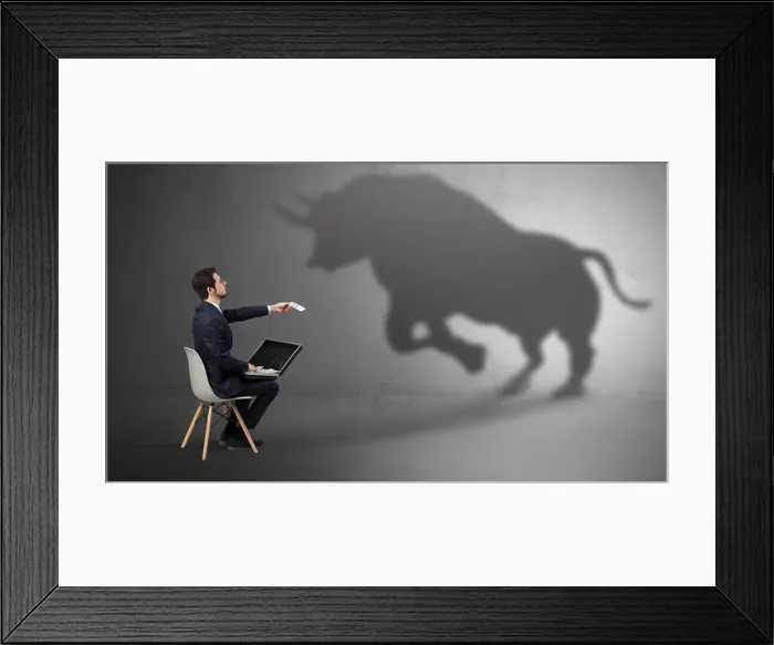 Framed Print : Humble businessman staying and offering stuffs to a huge angry bull shadow
