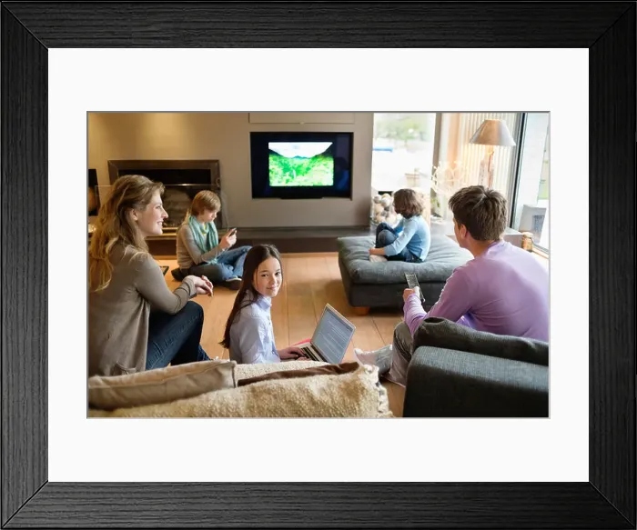Framed Print : Family using electronic gadgets in a living room Framed Print : Family using electronic gadgets in a living room