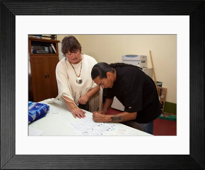 Framed Print : Native American man signs paperwork and documents in an office Framed Print : Native American man signs paperwork and documents in an office