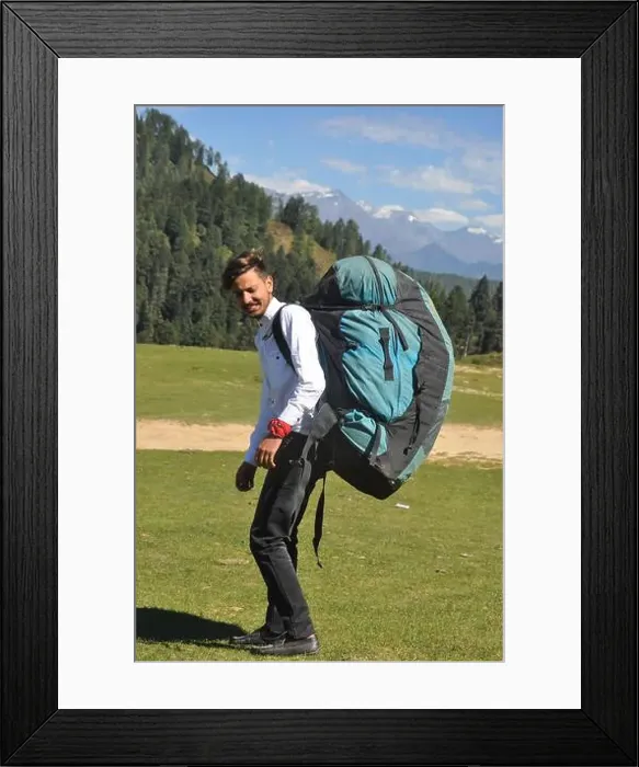 Framed Print : Rear view of a young male tourist walking with carrying parachute bag in the mountain Framed Print : Rear view of a young male tourist walking with carrying parachute bag in the mountain