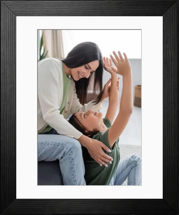 Framed Print : happy brunette babysitter sitting on couch and looking at cheerful kid with outstretched hands Framed Print : happy brunette babysitter sitting on couch and looking at cheerful kid with outstretched hands