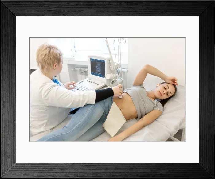 Framed Print : A professional doctor makes an ultrasound examination of a young girl who lies on a couch in the office Framed Print : A professional doctor makes an ultrasound examination of a young girl who lies on a couch in the office