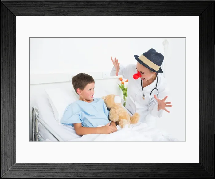 Framed Print : Doctor in clown costume entertaining ill boy in hospital Framed Print : Doctor in clown costume entertaining ill boy in hospital