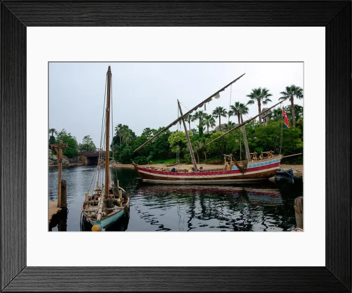 Framed Print : Two boats on the river with sails furled and the dock on the left. Palm trees in the background Framed Print : Two boats on the river with sails furled and the dock on the left. Palm trees in the background
