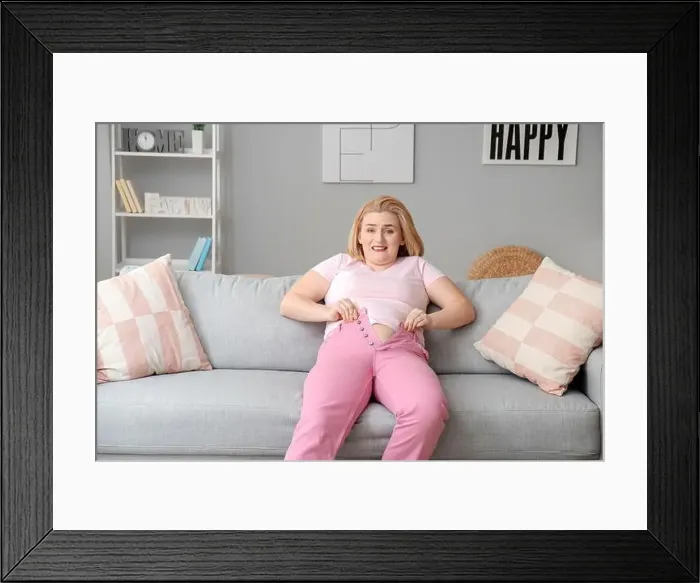 Framed Print : Troubled overweight woman in tight clothes at home Framed Print : Troubled overweight woman in tight clothes at home