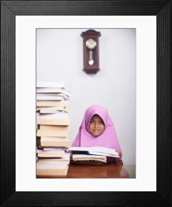 Framed Print : Little muslim girl in hijab reading a book and study at home Framed Print : Little muslim girl in hijab reading a book and study at home