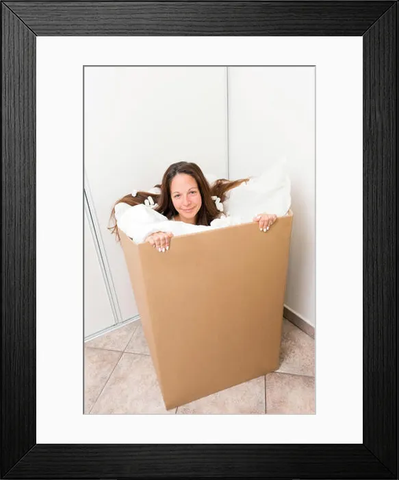 Framed Print : Young woman in a box with packing material Framed Print : Young woman in a box with packing material