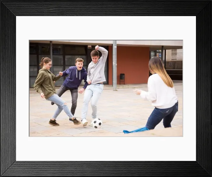 Framed Print : Teen friends spending time together outdoors playing with ball on square near school Framed Print : Teen friends spending time together outdoors playing with ball on square near school