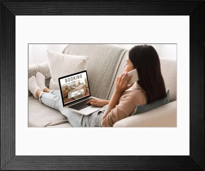 Framed Print : Girl booking hotel online, talking on phone with reservation team