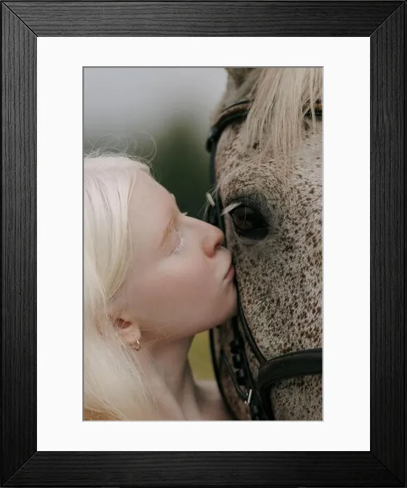 Framed Print : Portrait of young albino woman standing near gray horse and kisses it on meadow Framed Print : Portrait of young albino woman standing near gray horse and kisses it on meadow